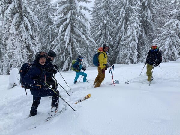 Skitourengeher:innen während der Abfahrt im Powder bei Schneefall im Goms