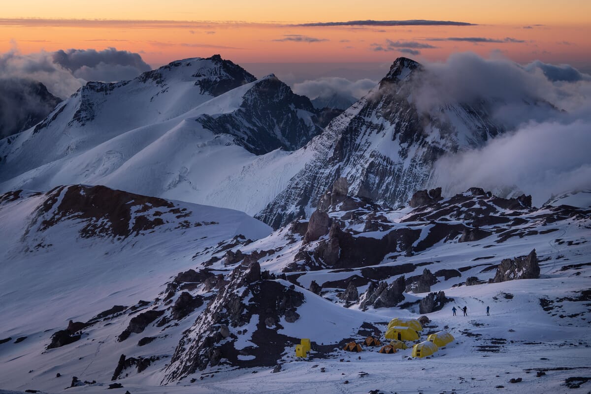 Mitten im Nationalpark Aconcagua: Abendstimmung, rot gefärbter Himmel, Bergsteiger und Zelte