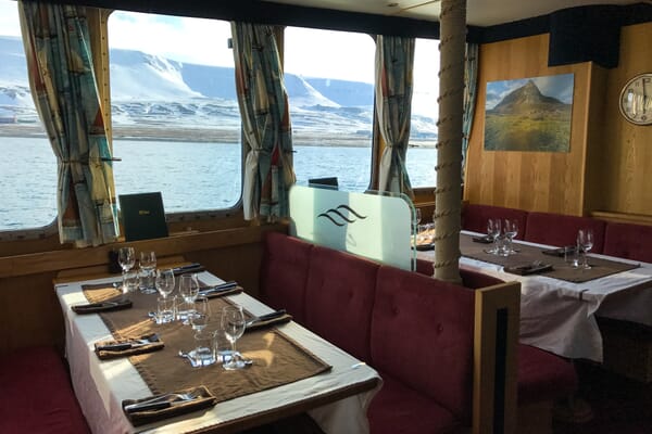 Essbereich auf dem Schiff Polaris, Blick durch die Fenster in die Schneeberge und aufs Wasser