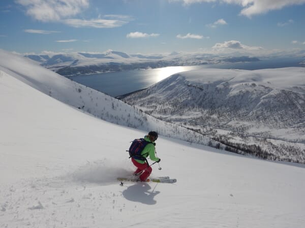 Skitourenfahrer in der Abfahrt mit Blick aufs Meer Skitourenfahrer in der Abfahrt mit Blick aufs Meer