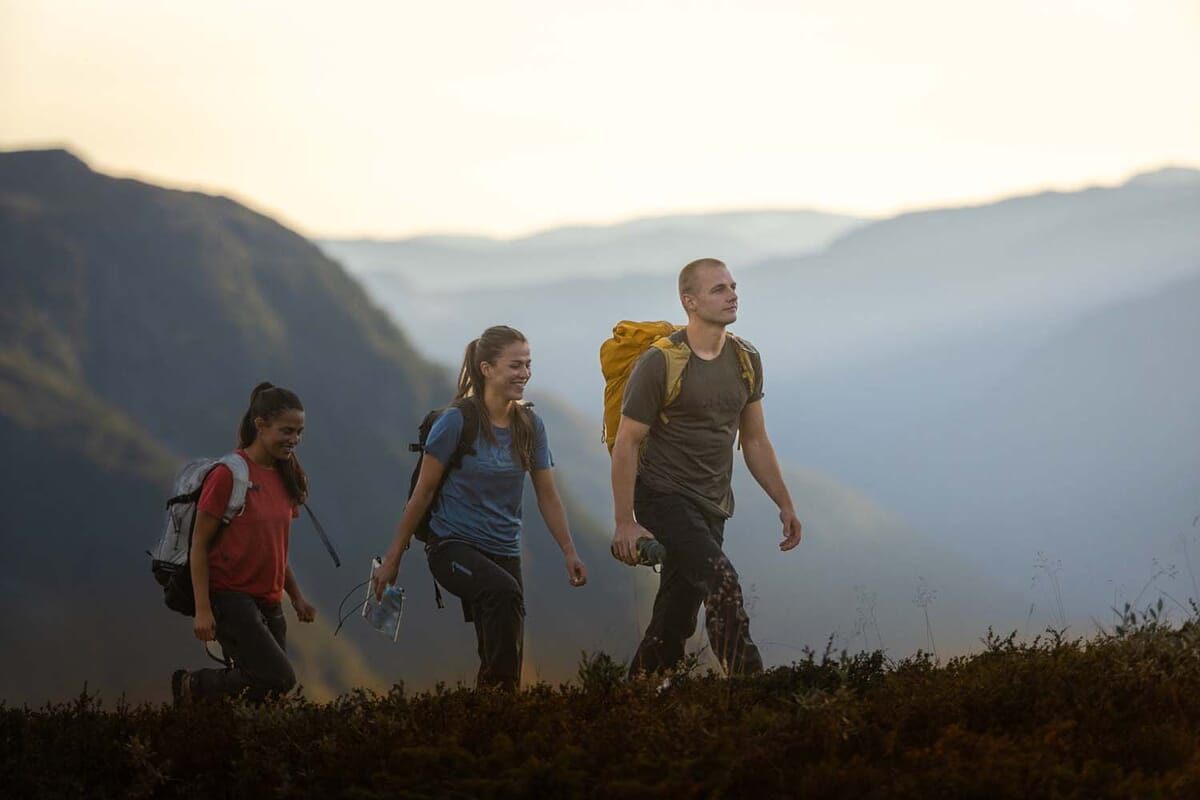 Drei Leute wandern im Gebirge bei Sonnenaufgang in Aclima-Bekleidung.