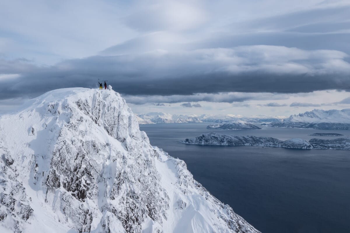 Skitourenreise Uloya, Gäste stehen auf dem Gipfel, weisse Hänge und blaues Meer