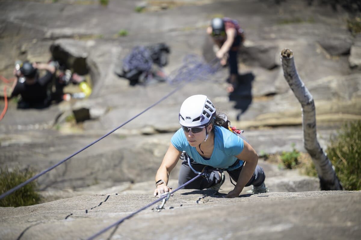Eine Kletterin im Toprope, Klettern draussen am Fels im Tessin, eine Person am Sichern