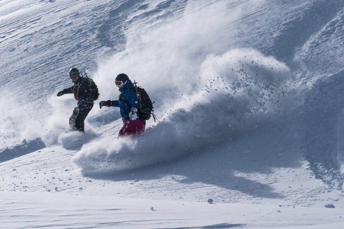 Zwei Snowboarder im Tiefschnee, stiebender Schnee, Powderabfahrt, Snowboardtouren