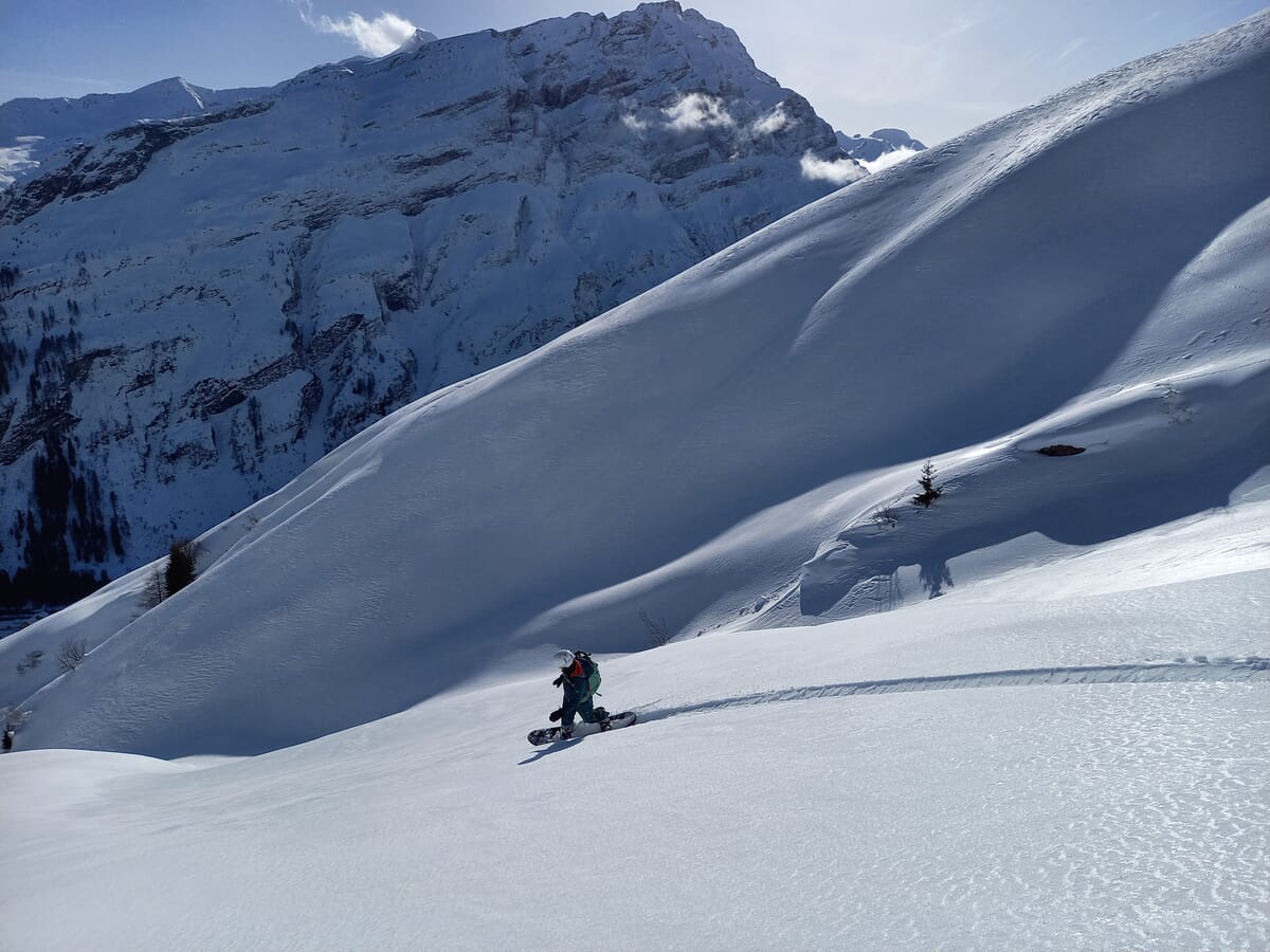 Stiebende Abfahrt im Pulverschnee mit Snowboard, Snowboarder auf Touren