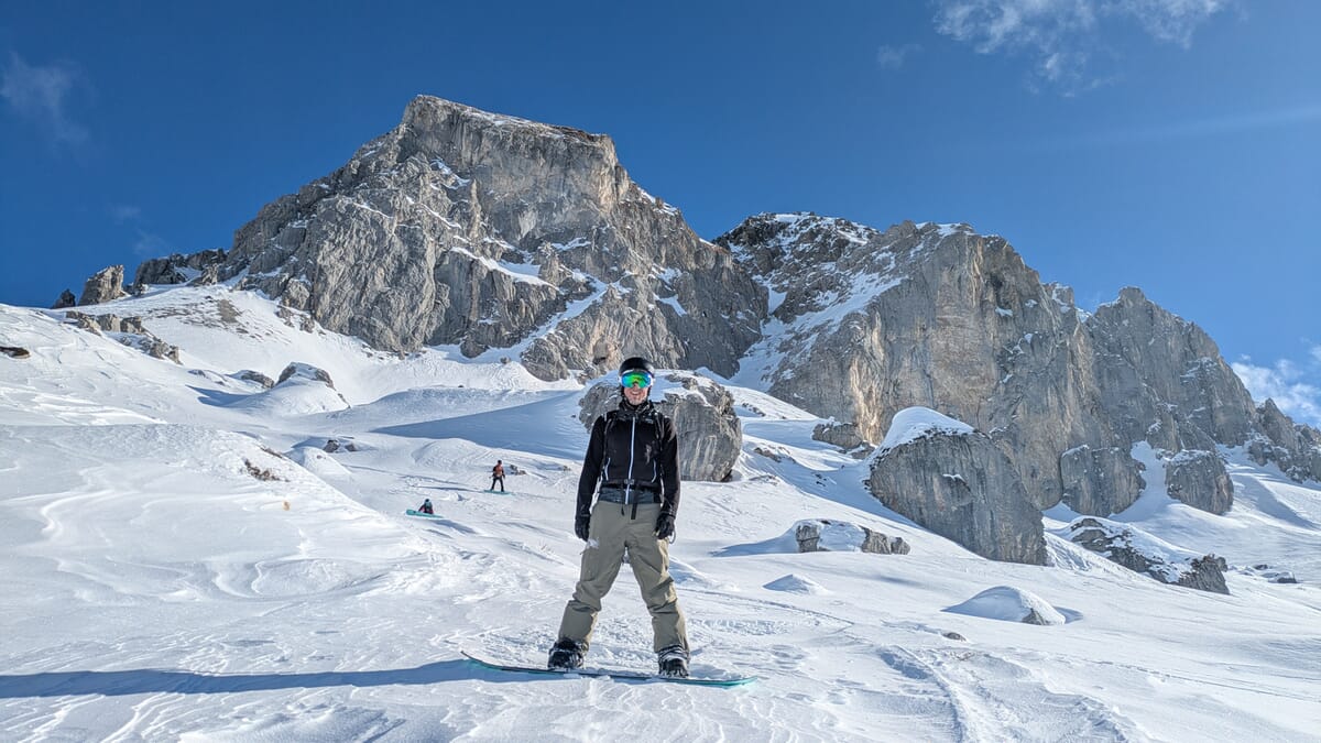Splitboard Touren, ein Snowboarder im Vordergrund, mehrere Snowboarder in der Abfahrt und schöne Berglandschaft