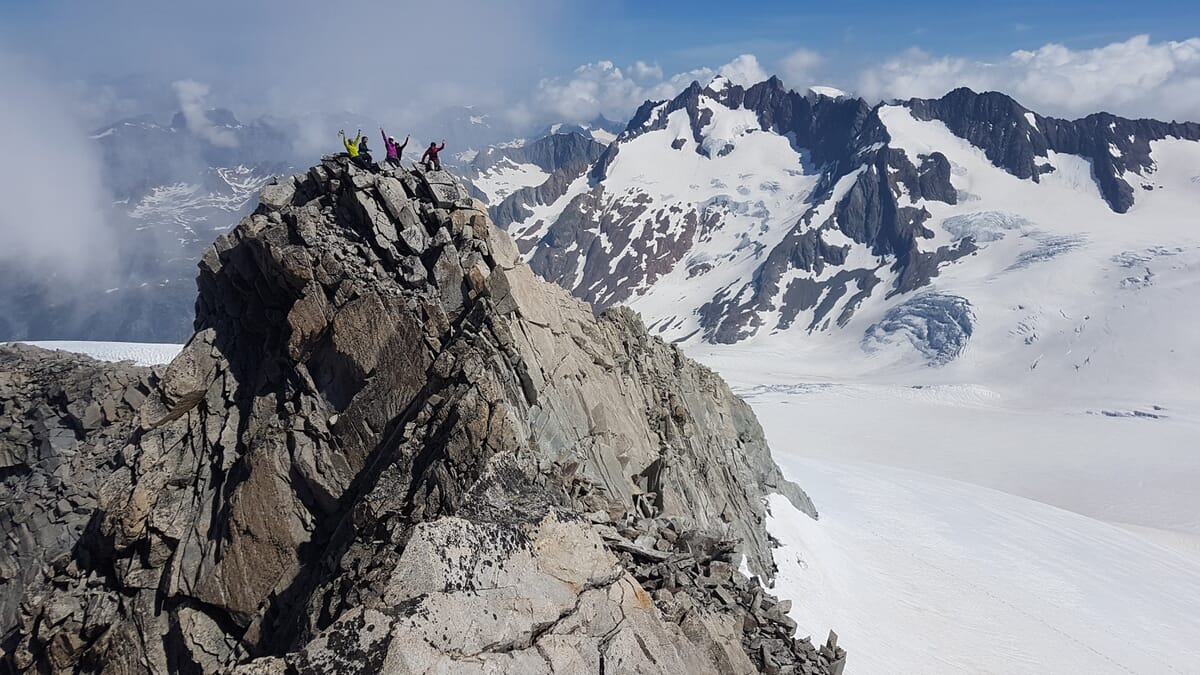 Fünf Bergsteiger am Gipfel auf einem imposanten Felsgrat | Gletscherlandschaft mit Spaltenzone und Berge