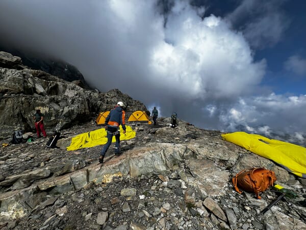 Bergsteiger mit Zelten auf felsigem Berg.