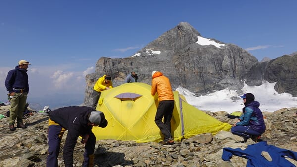 Bergsteiger bauen Zelt auf am Berg auf.