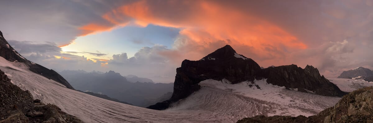 Berglandschaft mit schneebedeckten Gipfeln bei Sonnenuntergang.