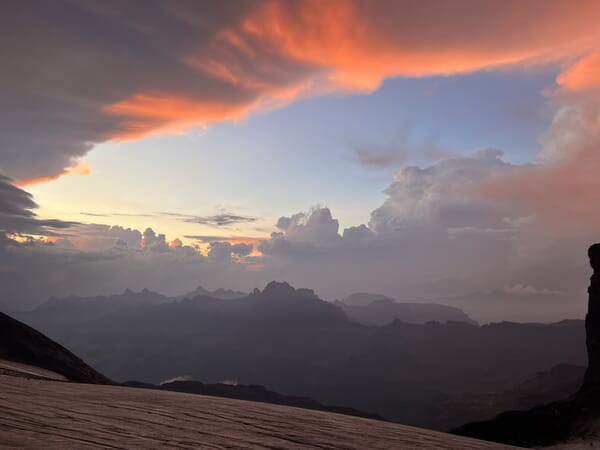 Berglandschaft bei Sonnenuntergang, wolkiger Himmel.
