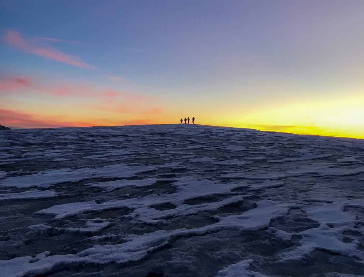 Bergsteiger am Horizont bei Sonnenaufgang auf Gletscher